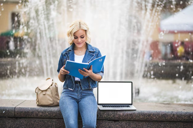 What Are the Most Remarkable Underrated Educational Travel Spots for Students? 2 pretty blonde girl woman student works her laptop computer read book near fountain city day 231208 4397